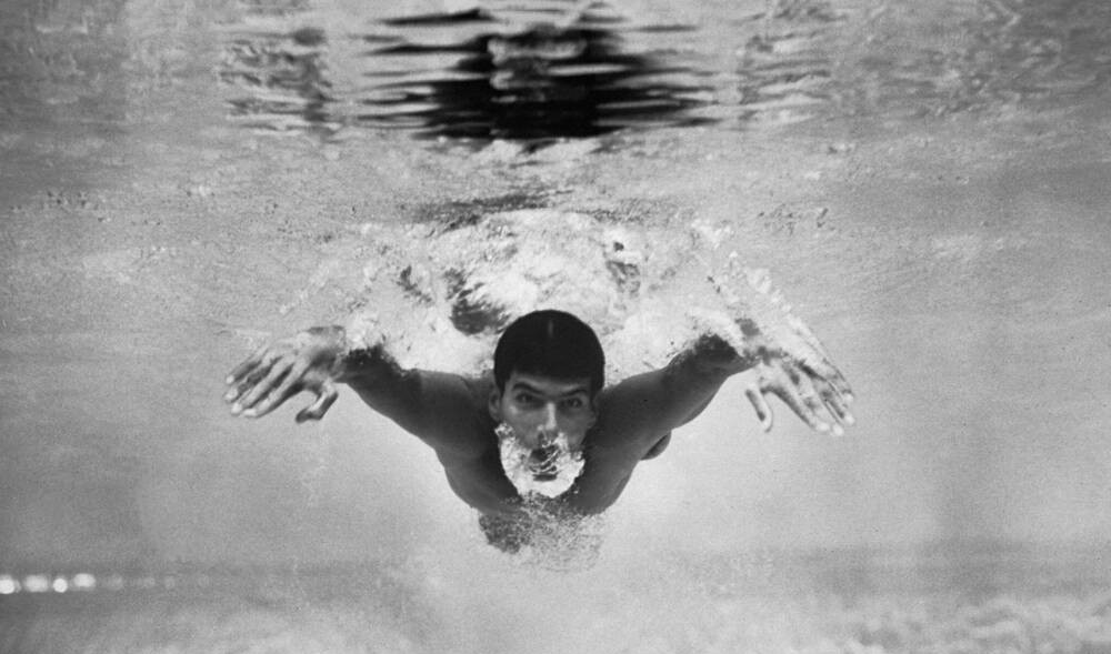 Underwater photograph: Mark Spitz swims butterfly toward the lens, arms wide and head out of the bubble trail, with his eyes completely open in the water and no goggles