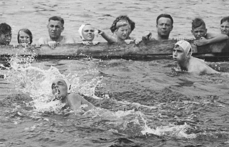 Zwei Schwimmer im Ziel, inmitten der Menge, auf einem Schwarz-Weiß-Foto