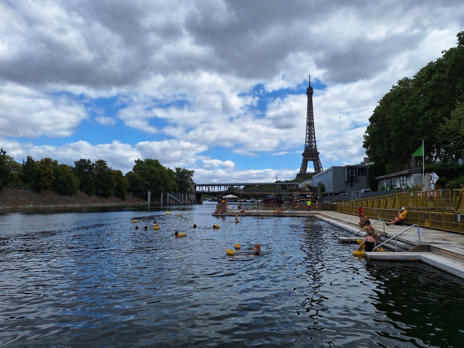 Bañistas con boyas amarillas en una piscina creada en el Sena, con la Torre Eiffel en el centro del encuadre