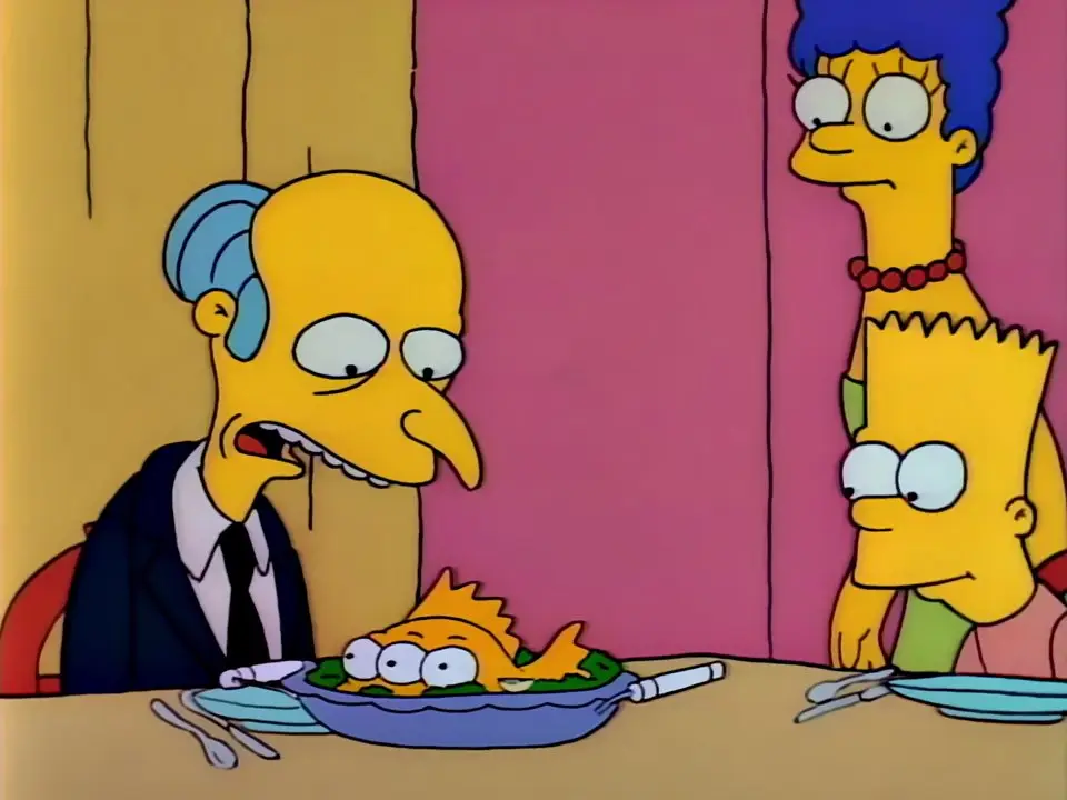 Fotograma dos Simpsons: o Sr. Burns sentado à mesa perante um prato com o peixe laranja de três olhos cozinhado, enquanto Marge e Bart o observam de pé atrás dele